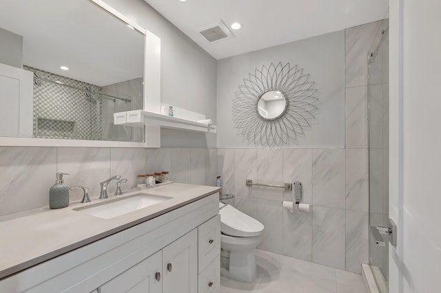 bathroom featuring a tile shower, toilet, tile walls, vanity, and tile patterned flooring