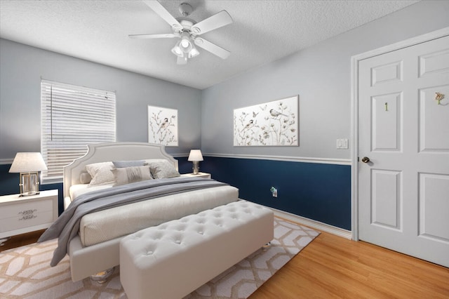 bedroom featuring ceiling fan, wood-type flooring, and a textured ceiling