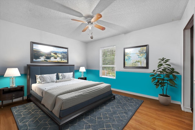 bedroom with ceiling fan, wood-type flooring, and a textured ceiling