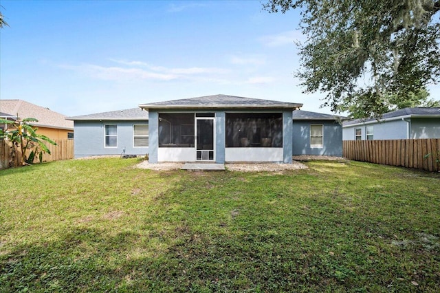 rear view of property with a yard and a sunroom