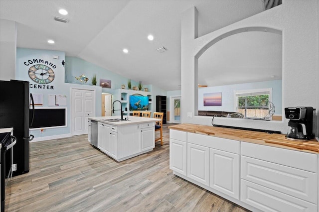 kitchen with lofted ceiling, a kitchen island with sink, light wood-type flooring, dishwasher, and butcher block counters