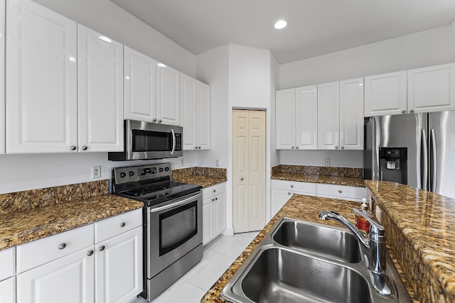 kitchen featuring stainless steel appliances, white cabinetry, sink, dark stone counters, and light tile patterned floors