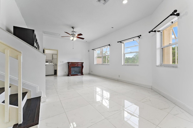 unfurnished living room with ceiling fan and washer / dryer