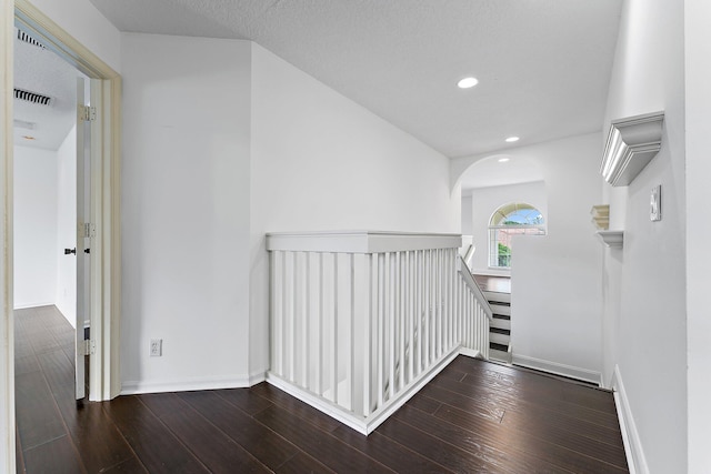 hallway featuring a textured ceiling and dark hardwood / wood-style flooring