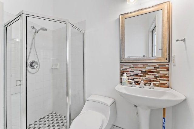 bathroom featuring toilet, an enclosed shower, and decorative backsplash