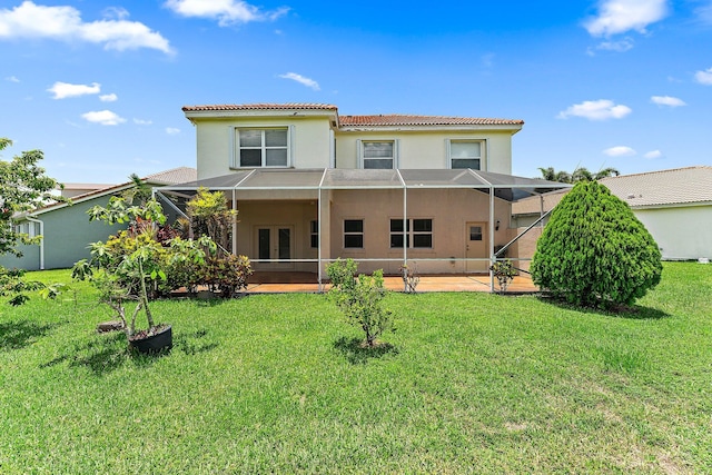 back of property with a patio, a lawn, and glass enclosure