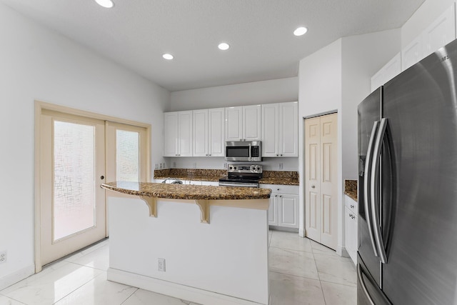 kitchen featuring dark stone counters, a kitchen island, appliances with stainless steel finishes, and white cabinets