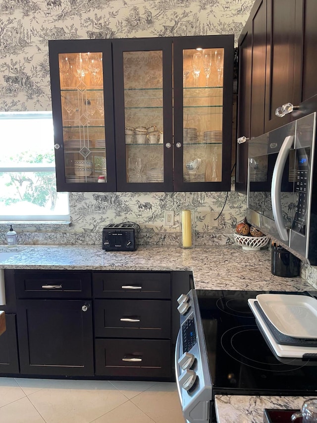 kitchen with light stone countertops, stove, and light tile patterned floors