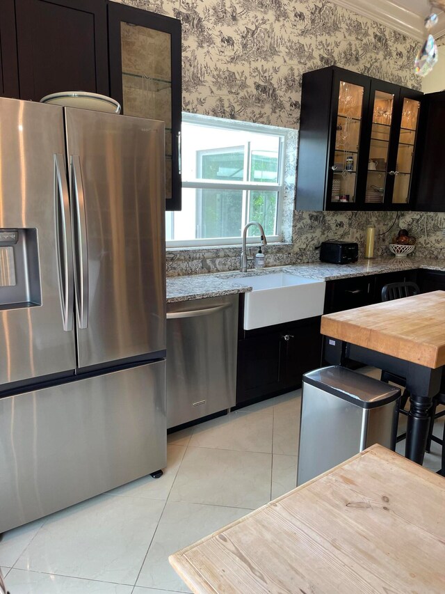 kitchen featuring sink, light stone counters, light tile patterned flooring, and stainless steel appliances