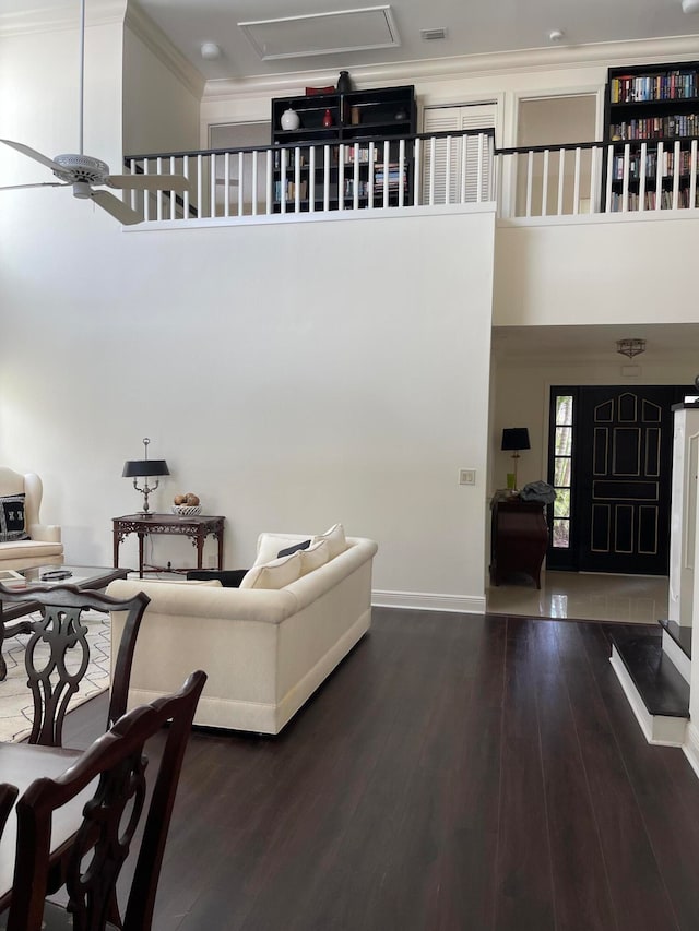 living room with a high ceiling, ceiling fan, dark hardwood / wood-style flooring, and ornamental molding