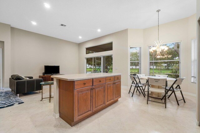 kitchen with light tile patterned flooring, an inviting chandelier, decorative light fixtures, and a kitchen island