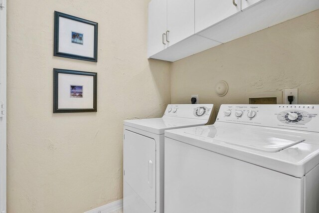 clothes washing area with washer and dryer and cabinets