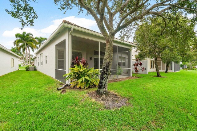 back of property with central AC, a yard, and a sunroom