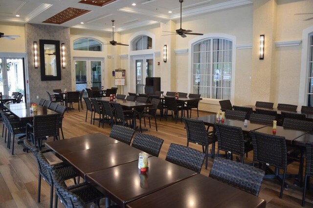 dining area featuring french doors, coffered ceiling, a high ceiling, wood-type flooring, and crown molding