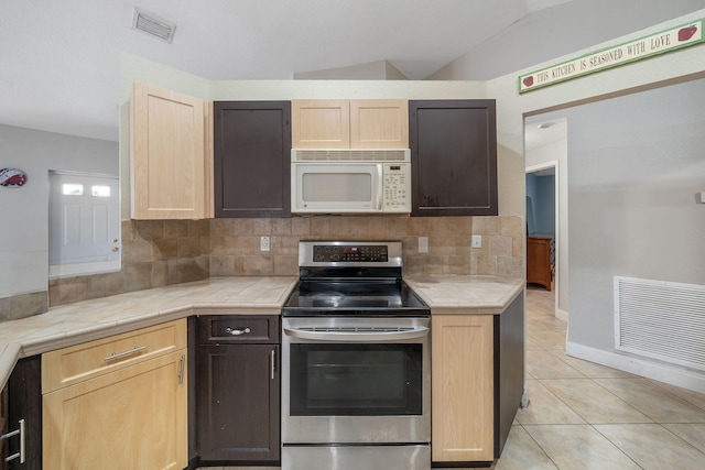 kitchen featuring light brown cabinetry, stainless steel electric range, lofted ceiling, and decorative backsplash