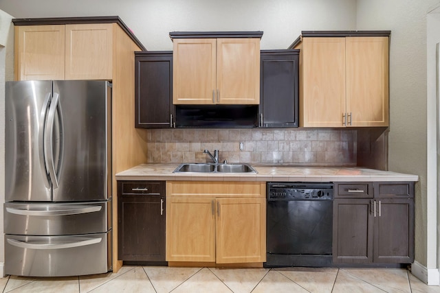 kitchen featuring dishwasher, sink, light tile patterned floors, stainless steel refrigerator, and tasteful backsplash