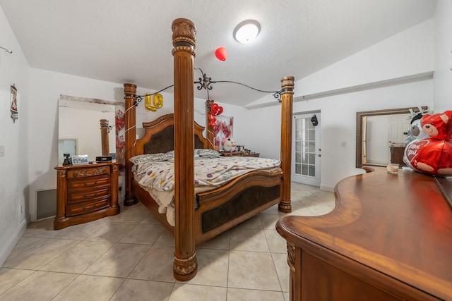 bedroom with a textured ceiling, light tile patterned floors, and vaulted ceiling