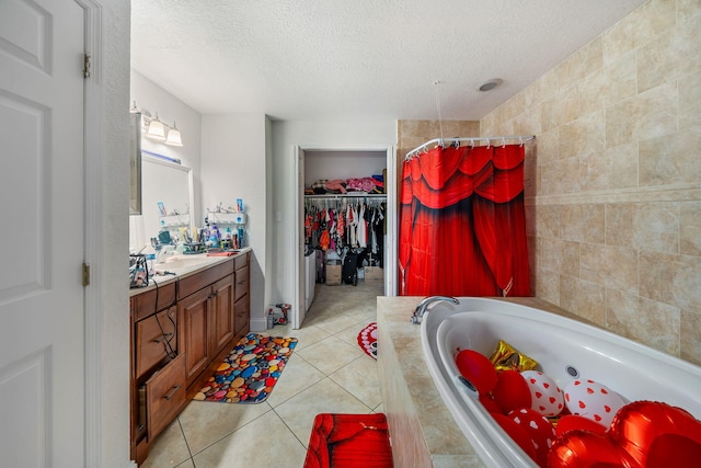 bathroom with tile patterned flooring, separate shower and tub, vanity, tile walls, and a textured ceiling