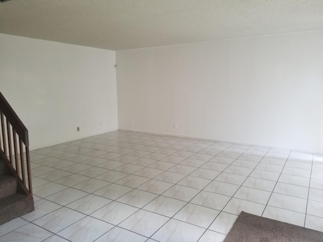 tiled empty room with a textured ceiling