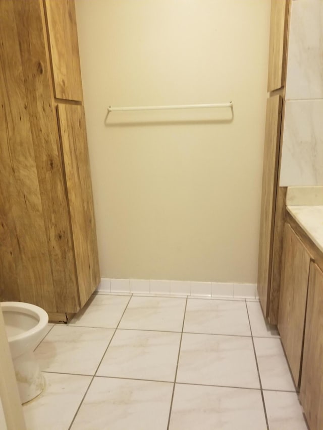 bathroom with toilet, vanity, and tile patterned floors