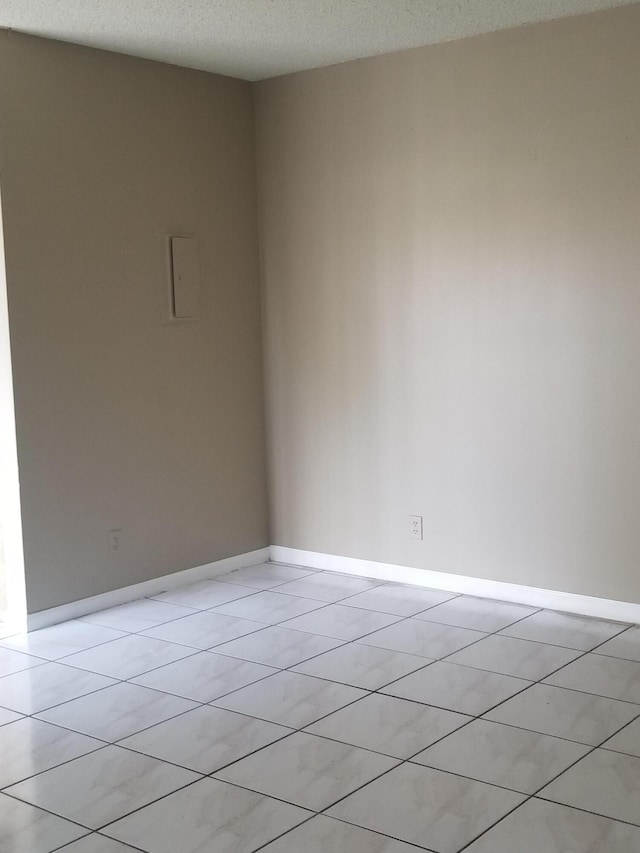 tiled empty room featuring a textured ceiling