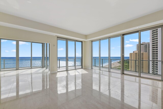 unfurnished room featuring a water view and a view of the beach