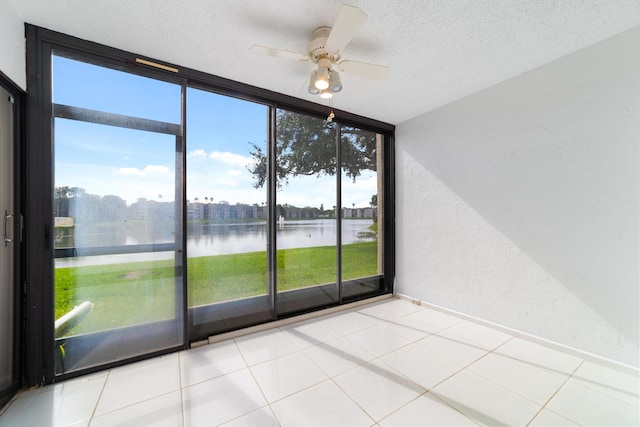 6093 Pointe Regal Cir Unit 106, Delray Beach, FL 33484 - empty room featuring a textured wall, a water view, ceiling fan, a wall of windows, and a textured ceiling