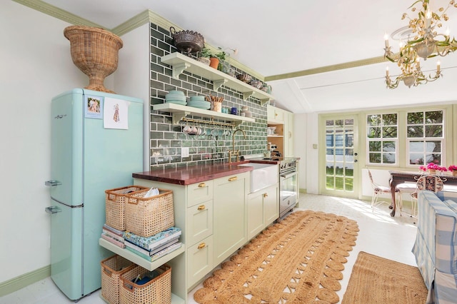 kitchen with decorative backsplash, crown molding, stainless steel stove, white fridge, and vaulted ceiling