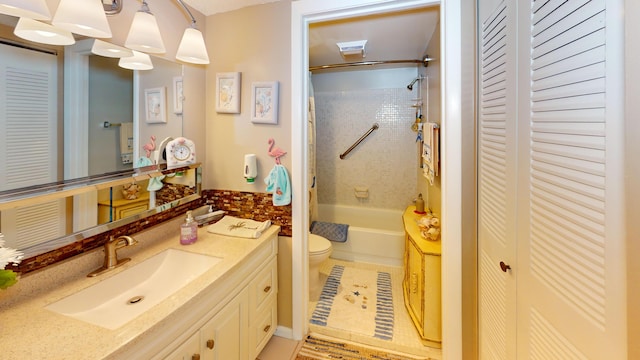 full bathroom featuring tiled shower / bath, vanity, toilet, and tile patterned flooring