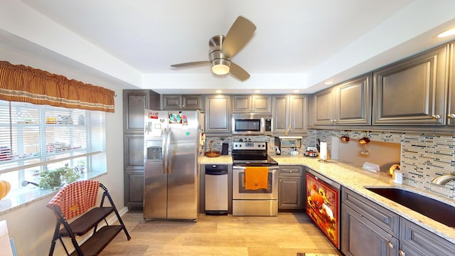 kitchen featuring light stone countertops, appliances with stainless steel finishes, light wood-type flooring, and decorative backsplash