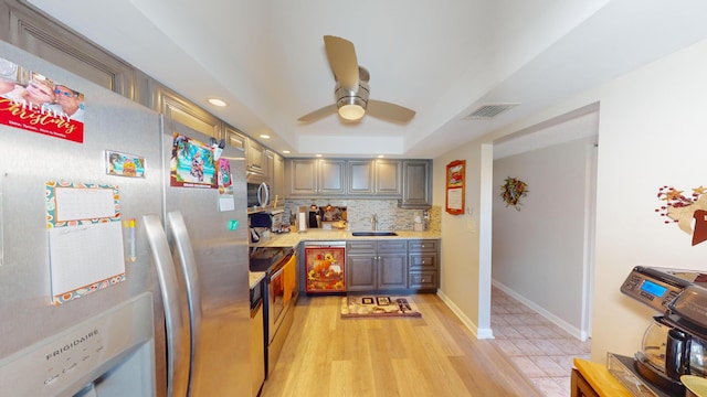 kitchen with ceiling fan, backsplash, sink, light hardwood / wood-style floors, and stainless steel appliances