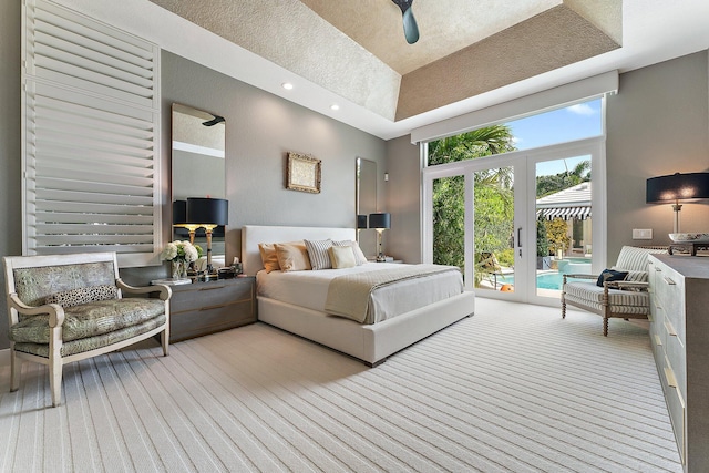 carpeted bedroom with a high ceiling, french doors, ceiling fan, access to exterior, and a tray ceiling