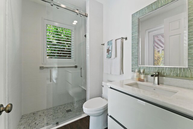 bathroom with hardwood / wood-style floors, vanity, toilet, and a shower with shower door