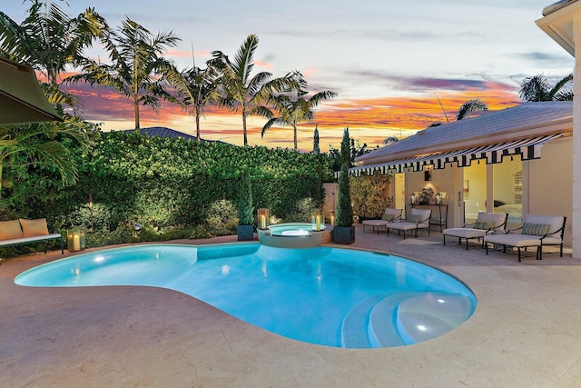 pool at dusk with an in ground hot tub and a patio