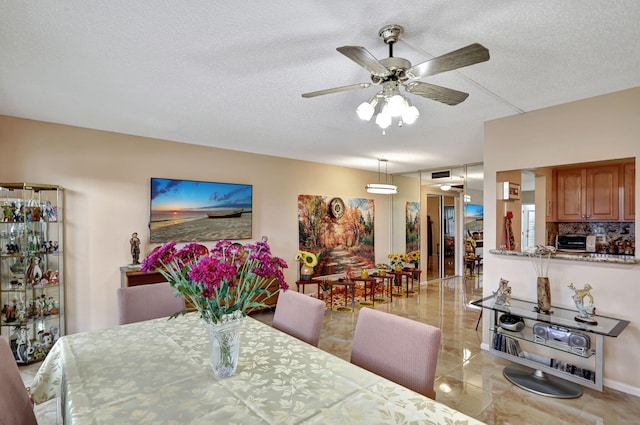 dining area with a textured ceiling and ceiling fan