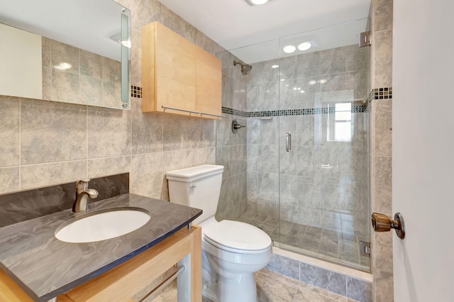 bathroom featuring walk in shower, vanity, toilet, and tile walls