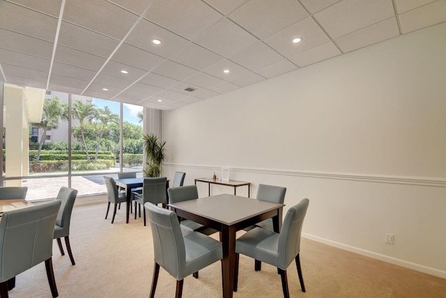 carpeted dining area with a paneled ceiling