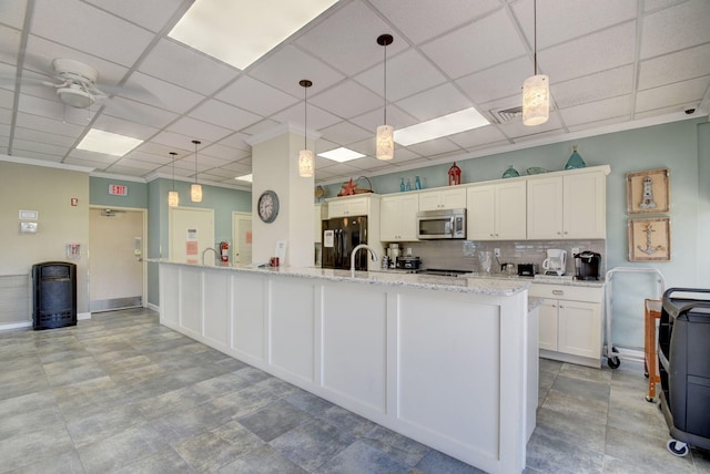 kitchen with white cabinetry, black refrigerator, pendant lighting, and a drop ceiling