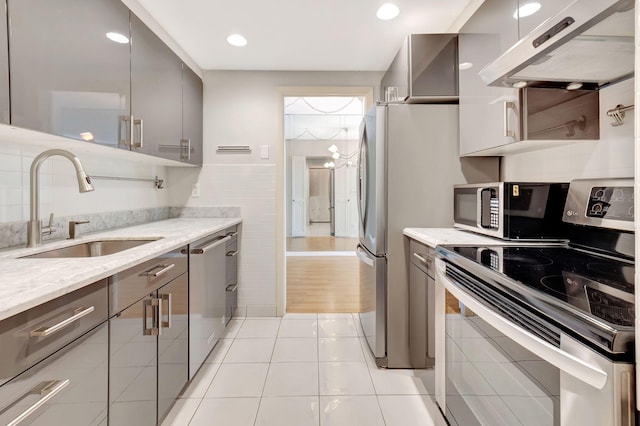 kitchen featuring light tile patterned flooring, sink, light stone counters, stainless steel appliances, and exhaust hood