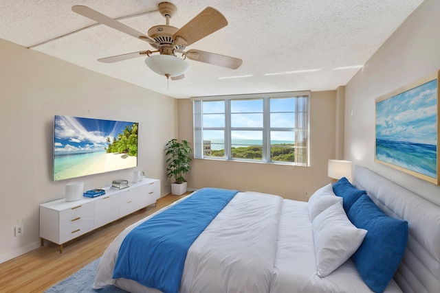 bedroom featuring a textured ceiling, light hardwood / wood-style floors, and ceiling fan