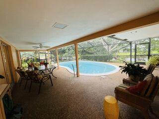 view of pool with a lanai, ceiling fan, and a patio