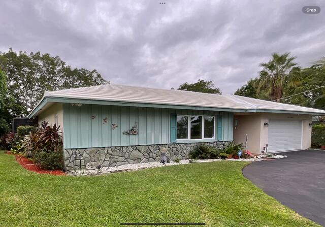 single story home featuring a garage and a front lawn