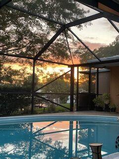 pool at dusk featuring glass enclosure