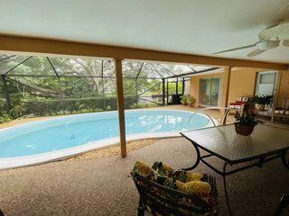 view of pool with ceiling fan and glass enclosure