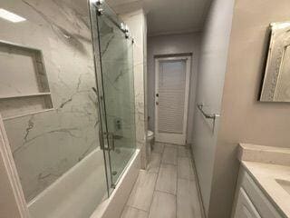 full bathroom with vanity, bath / shower combo with glass door, and toilet