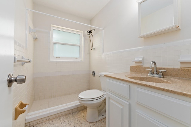 bathroom featuring vanity, toilet, tile walls, and tiled shower