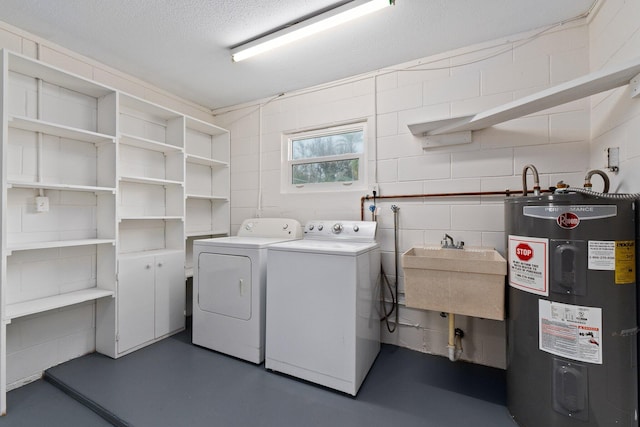 clothes washing area featuring a textured ceiling, water heater, sink, and washer and dryer