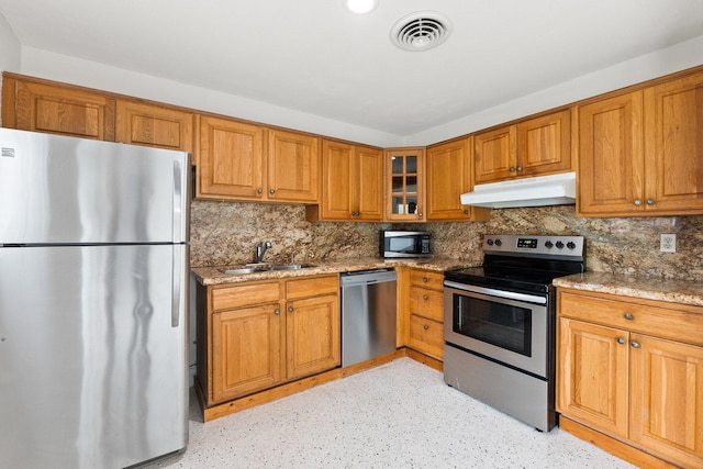 kitchen featuring light stone countertops, sink, appliances with stainless steel finishes, and backsplash