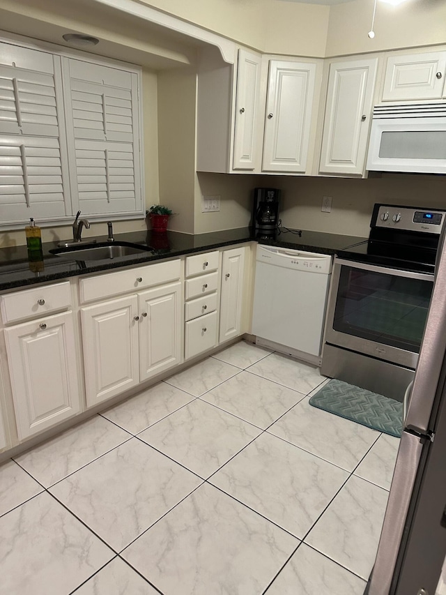 kitchen with white appliances, a sink, white cabinets, and dark countertops
