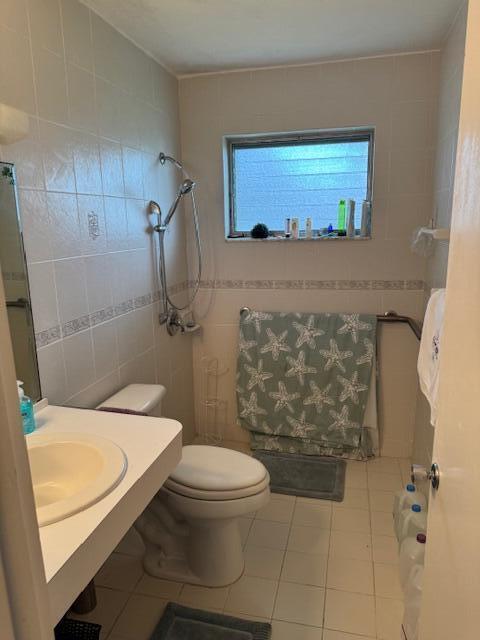 bathroom with tile patterned flooring, toilet, and tile walls